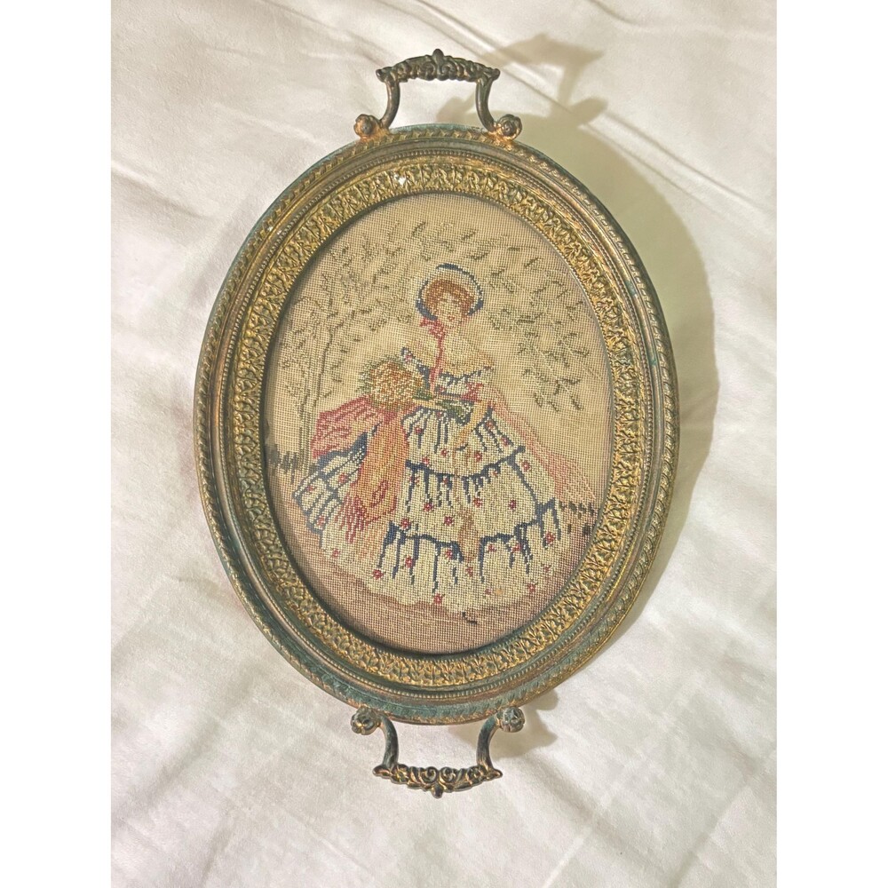 antique needlepoint of woman on linen. brass frame